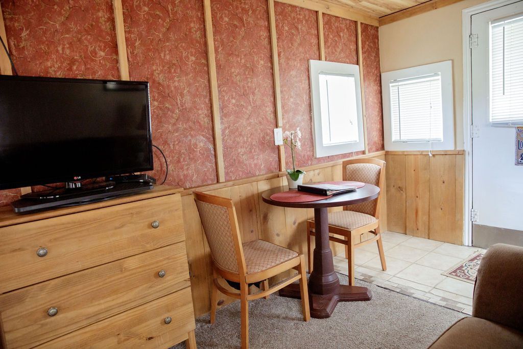 A living room with a table , chairs , dresser and television.