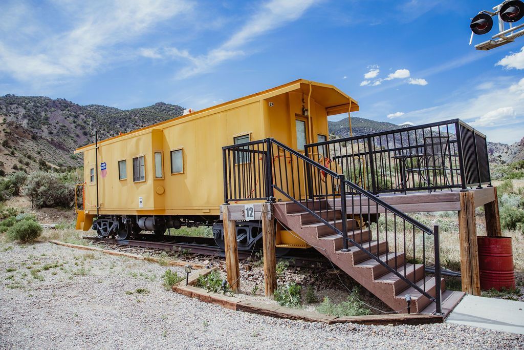 A yellow train car with stairs leading up to it.