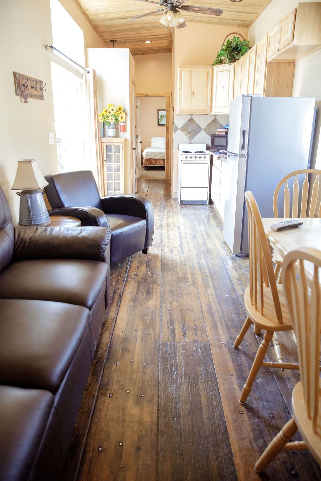 A living room with a couch , chairs , a table and a refrigerator.