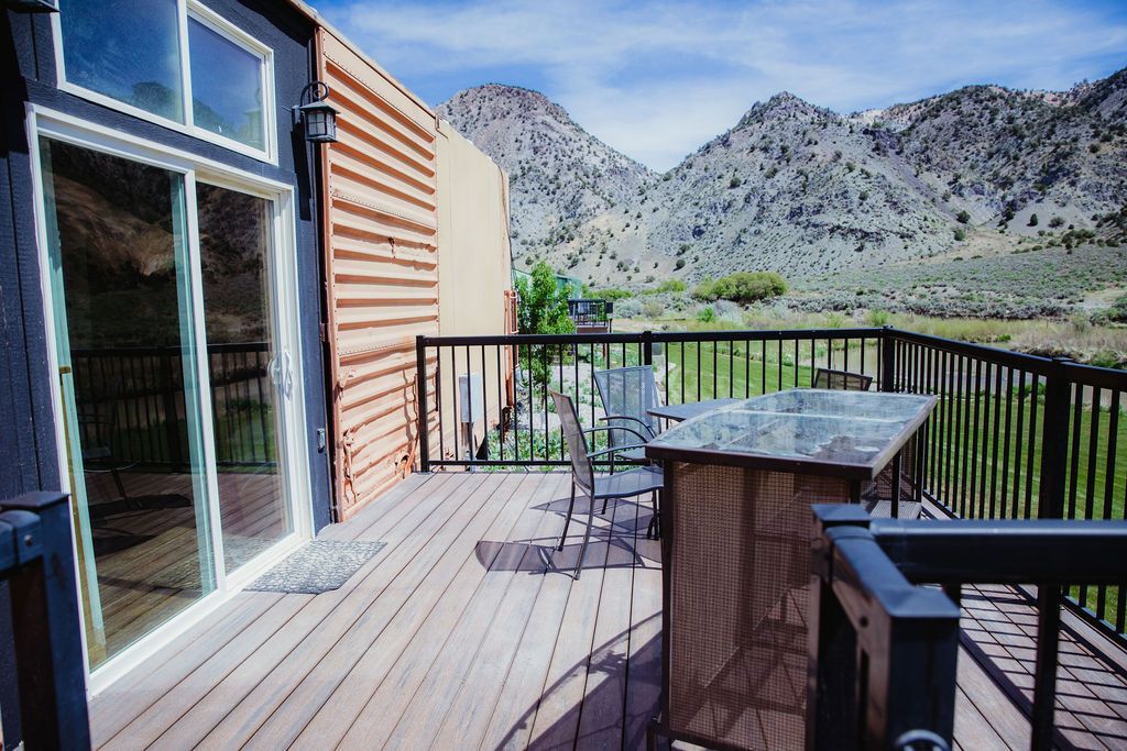 A deck with a table and chairs and mountains in the background