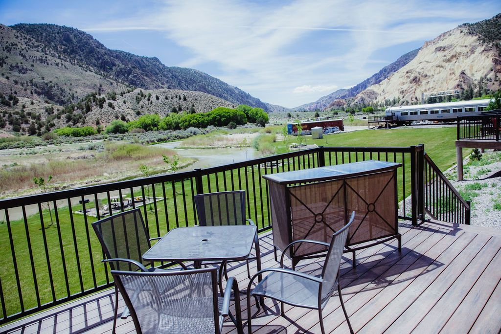 A deck with a table and chairs and mountains in the background