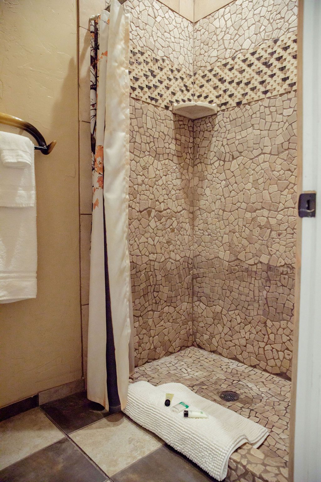 A bathroom with a walk in shower and a towel on the floor.