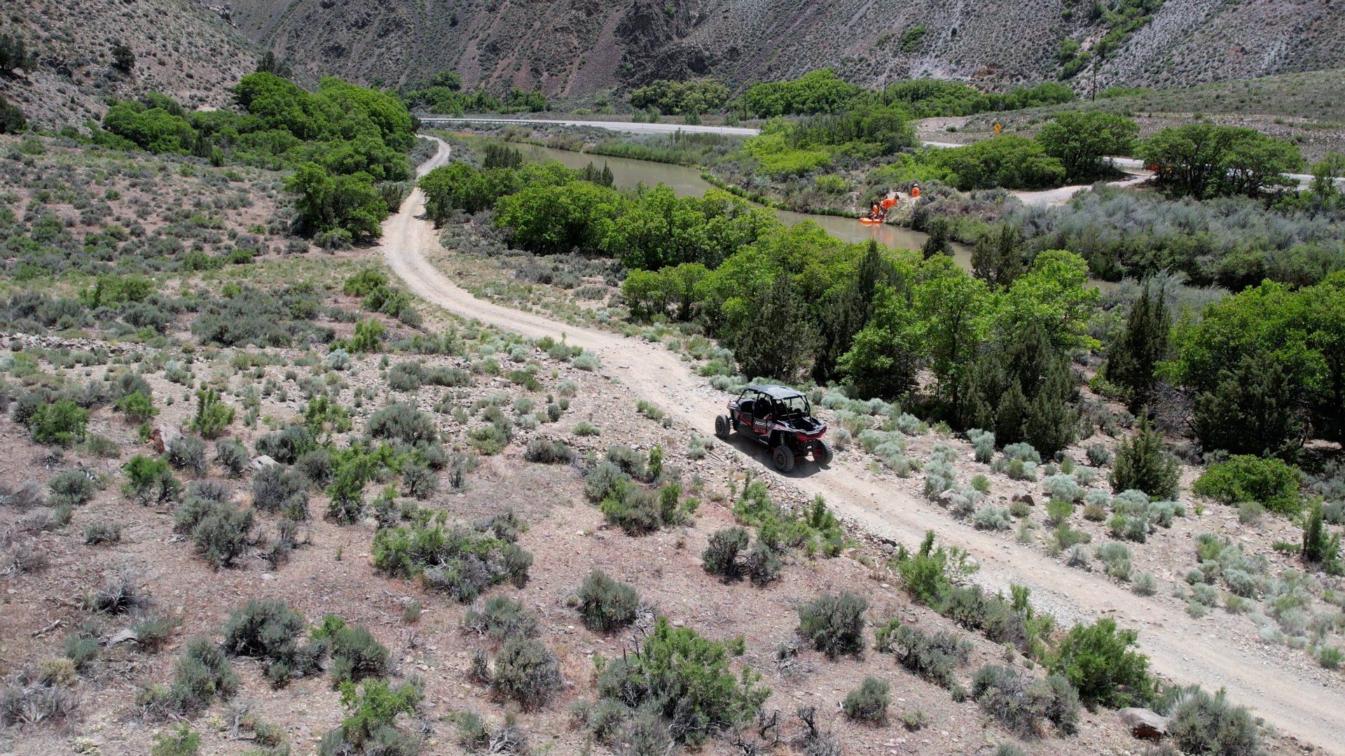An aerial view of a jeep driving down a dirt road.