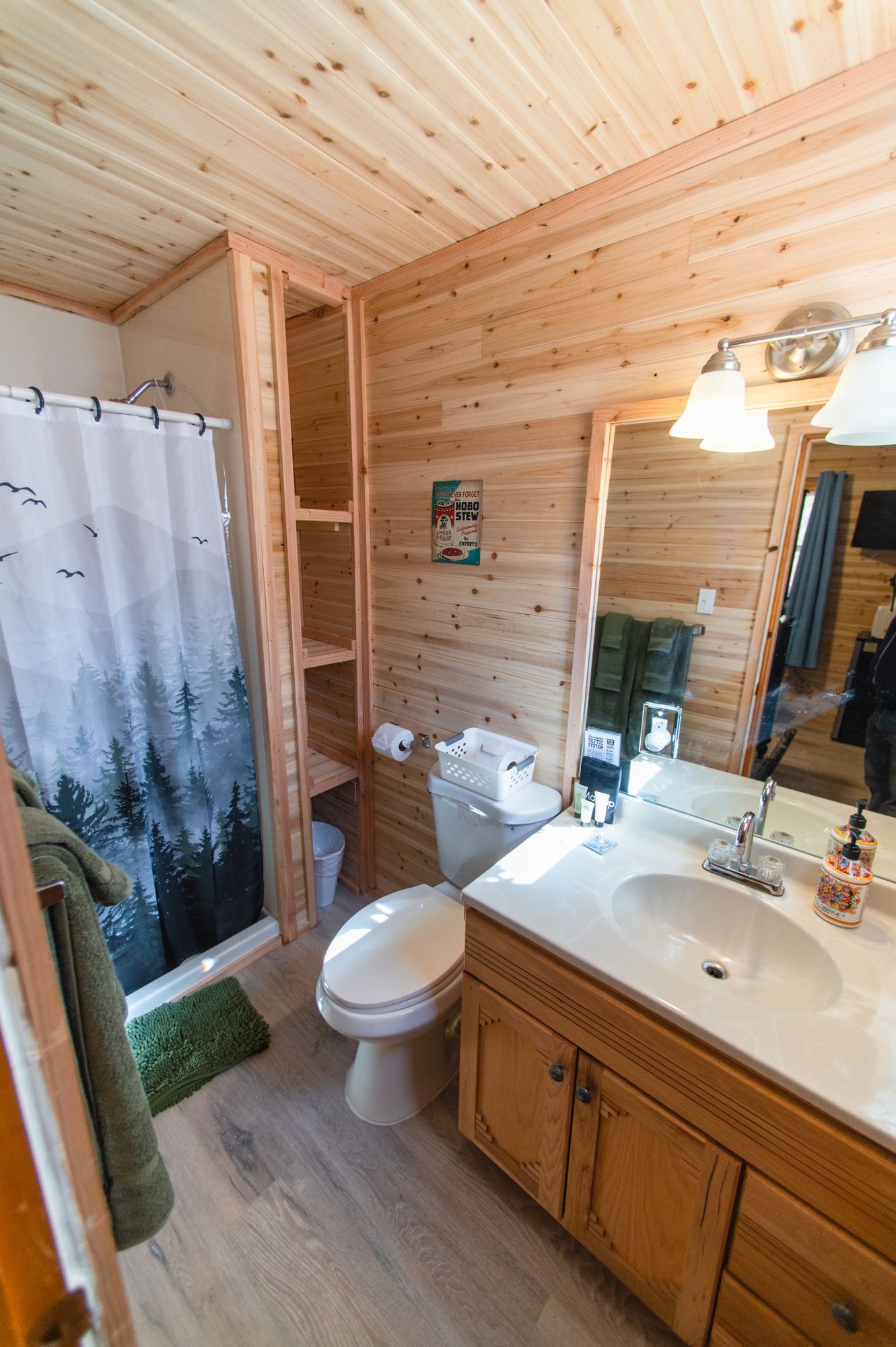 A bathroom with a toilet , sink , mirror and shower curtain.