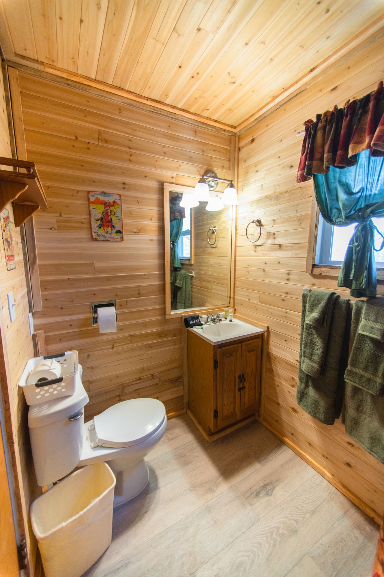 A bathroom in a log cabin with a toilet , sink and mirror.