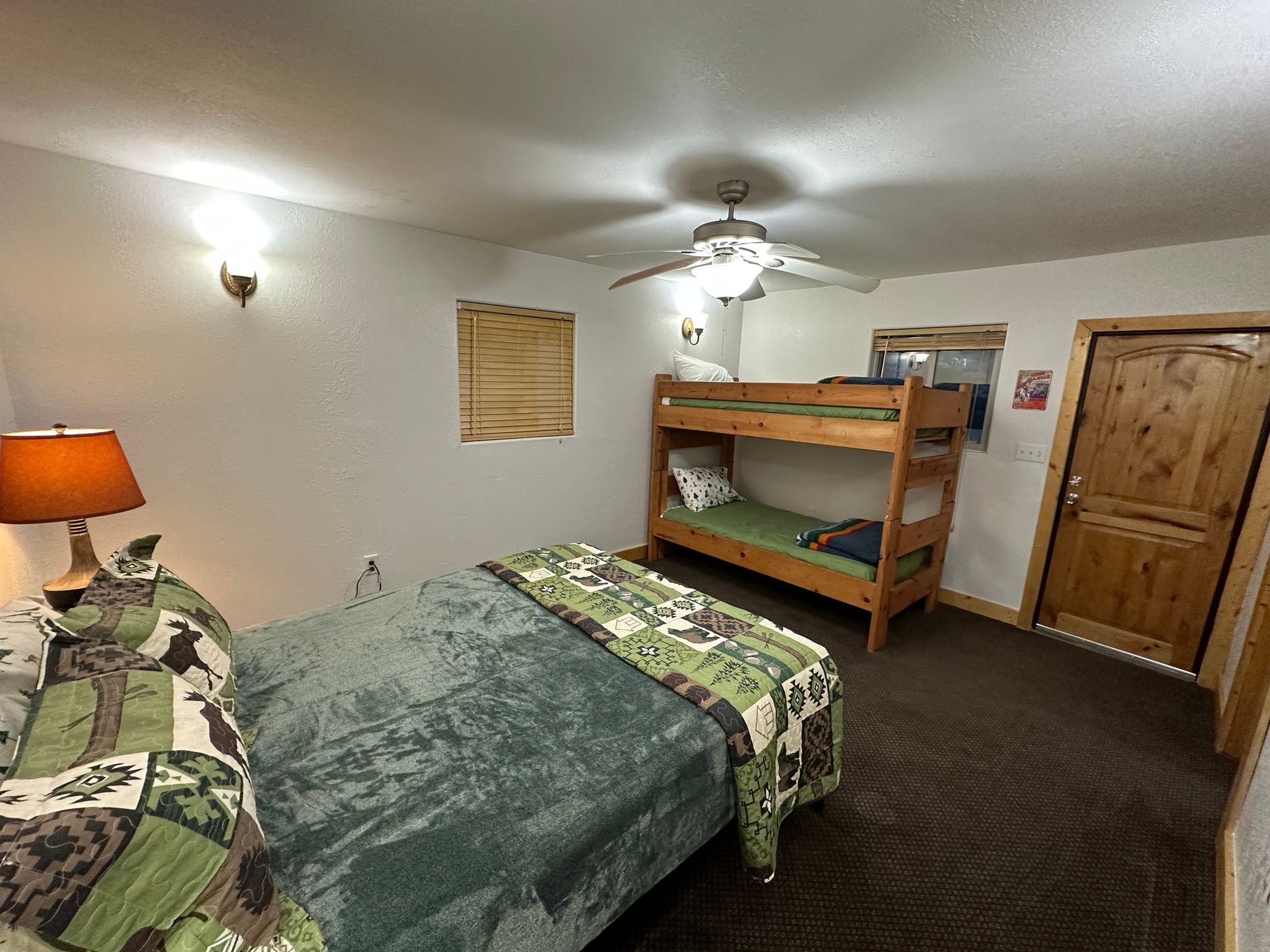 A bedroom with a bunk bed , a bed , and a ceiling fan.