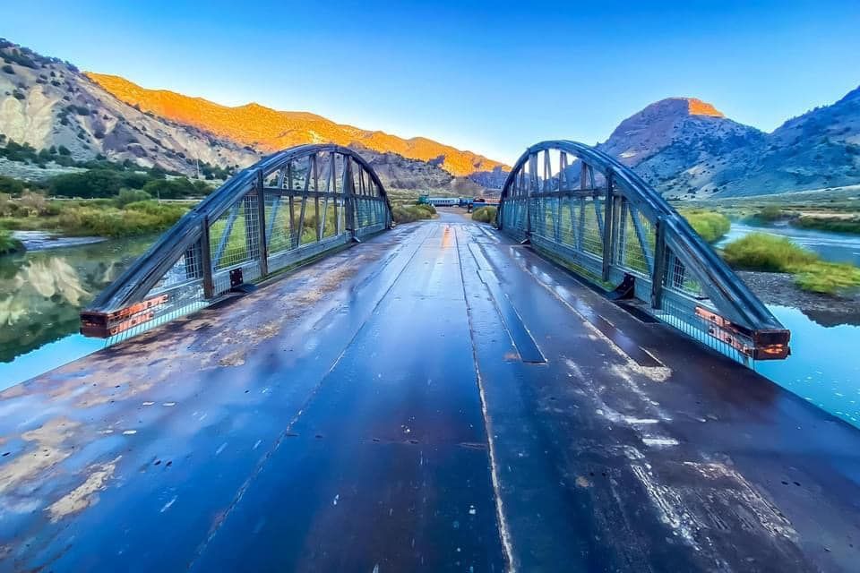 A bridge over a river with mountains in the background.