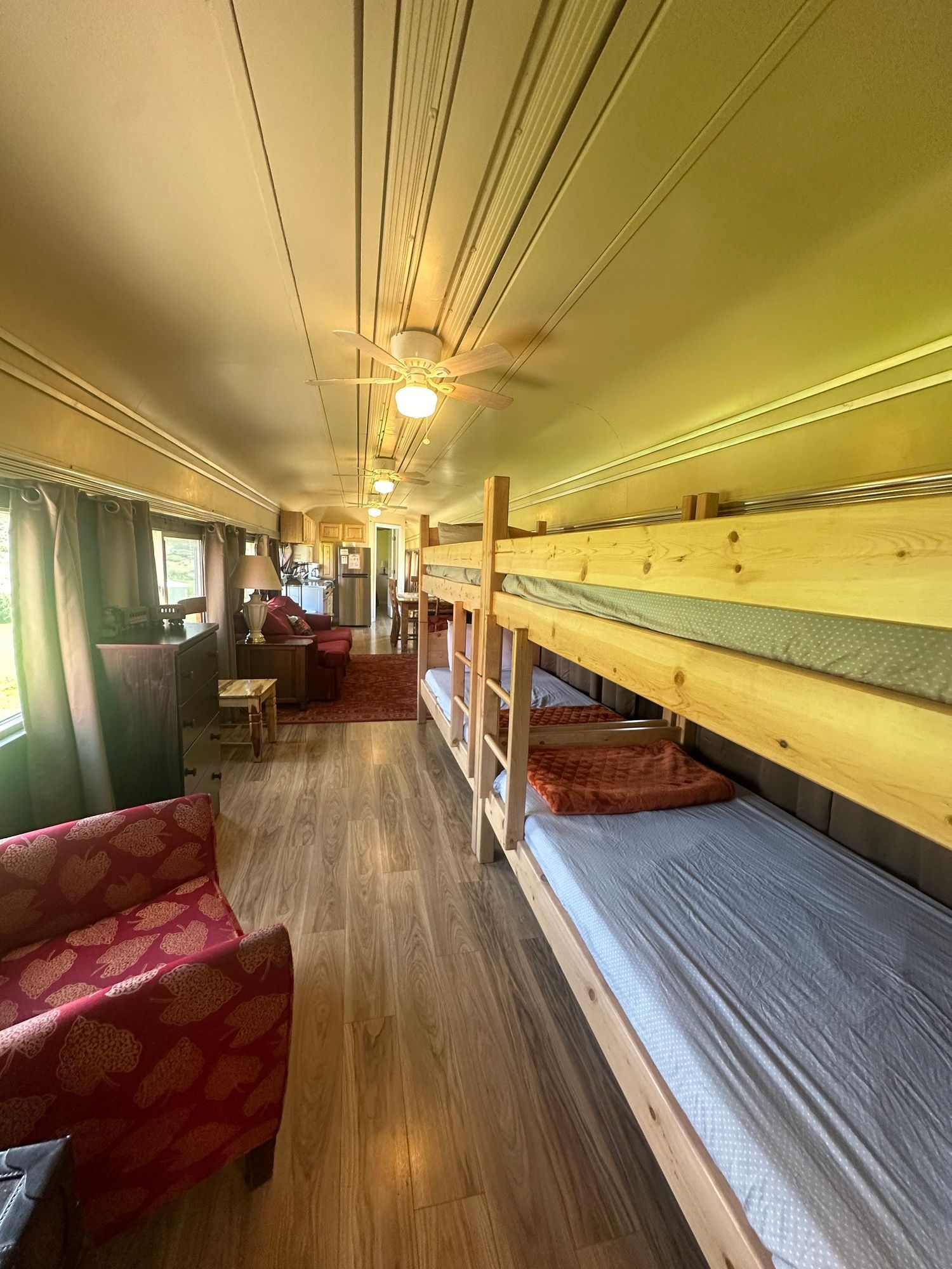 A room with bunk beds , chairs , and a ceiling fan.