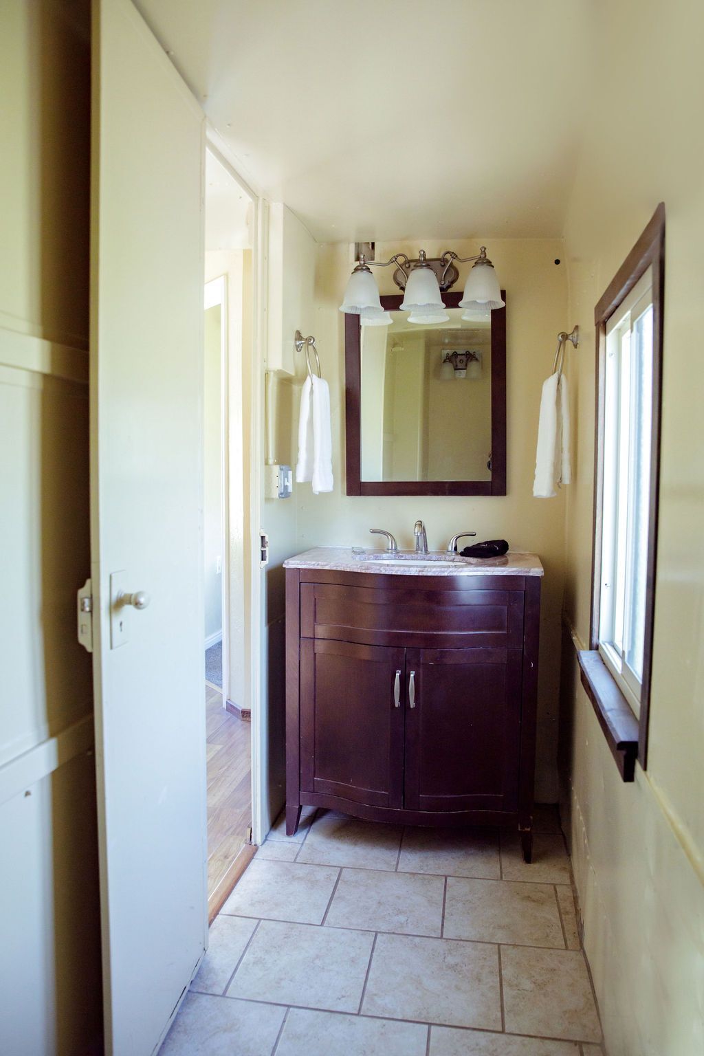 A bathroom with a sink , mirror and window