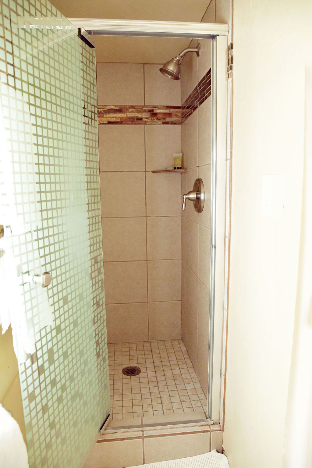 A bathroom with a walk in shower with a glass door