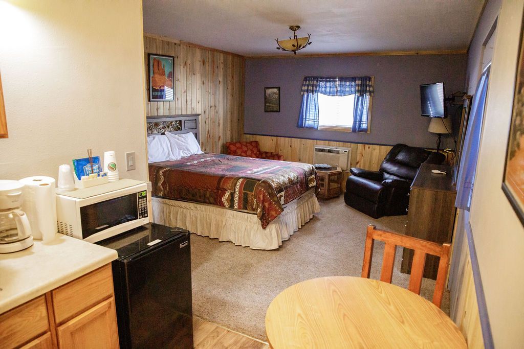 A hotel room with a table , chairs , a microwave and a refrigerator.