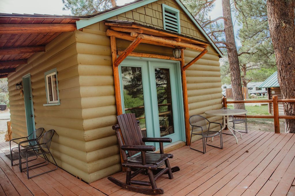 There is a rocking chair on the deck of a log cabin.