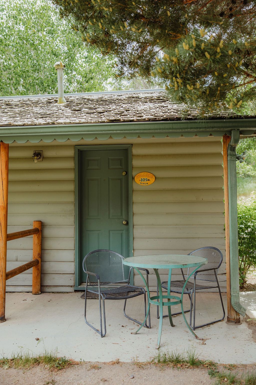 A small cabin with a table and chairs on the porch.