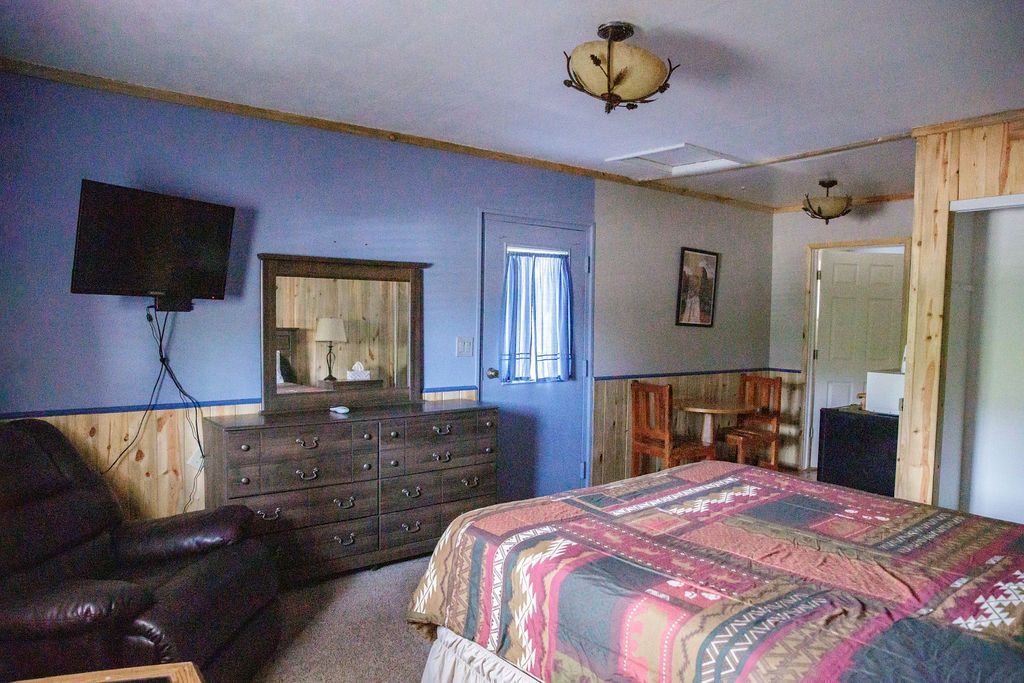 A bedroom with a bed , dresser , chair and television.