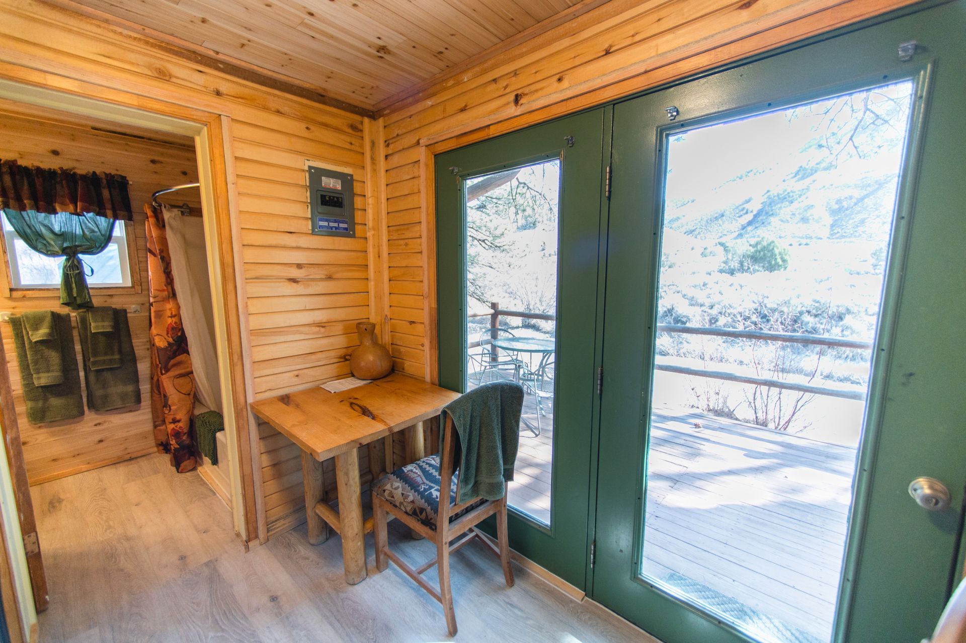 A wooden cabin with a desk and chair and a large window.