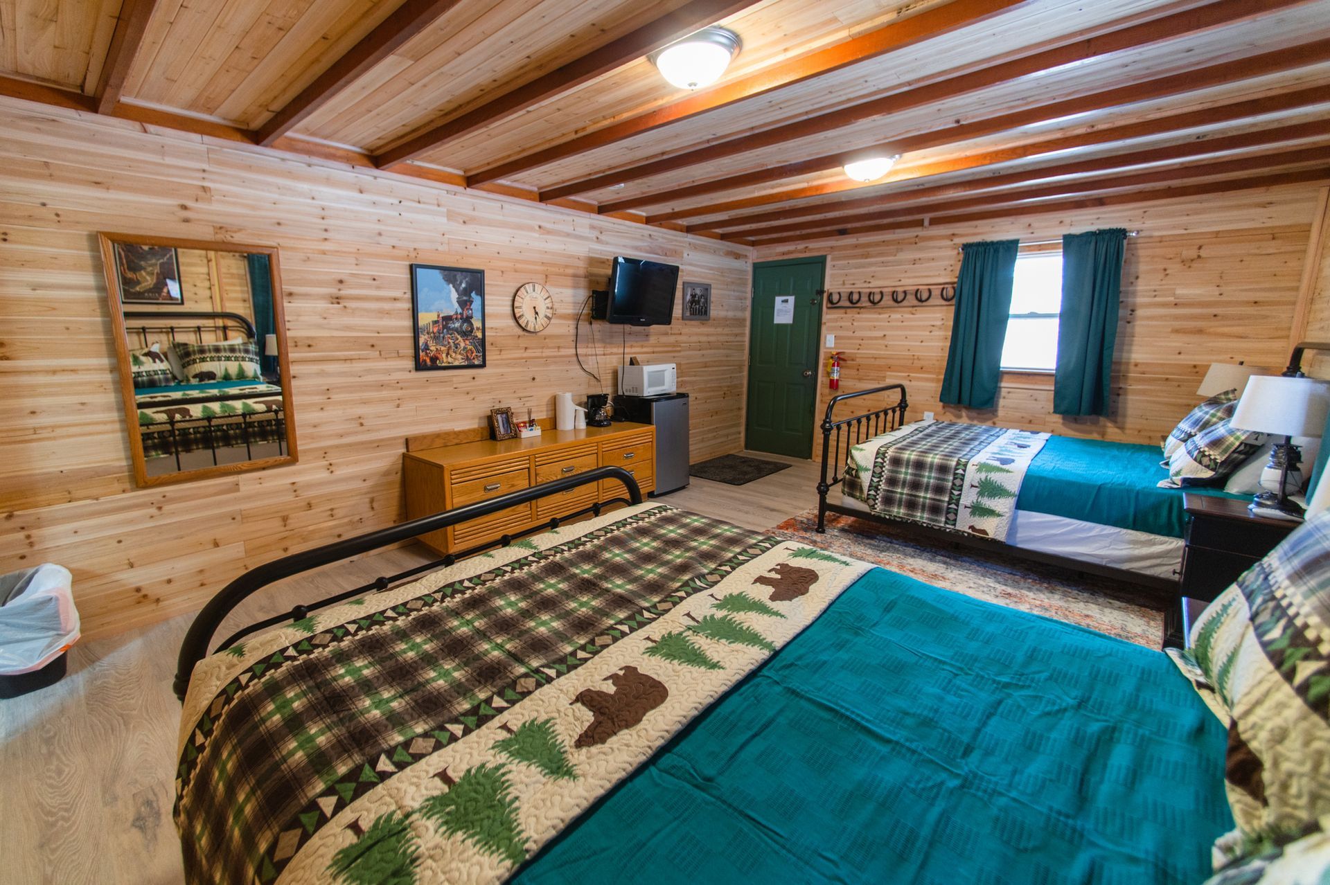 A bedroom in a cabin with two beds and a dresser.