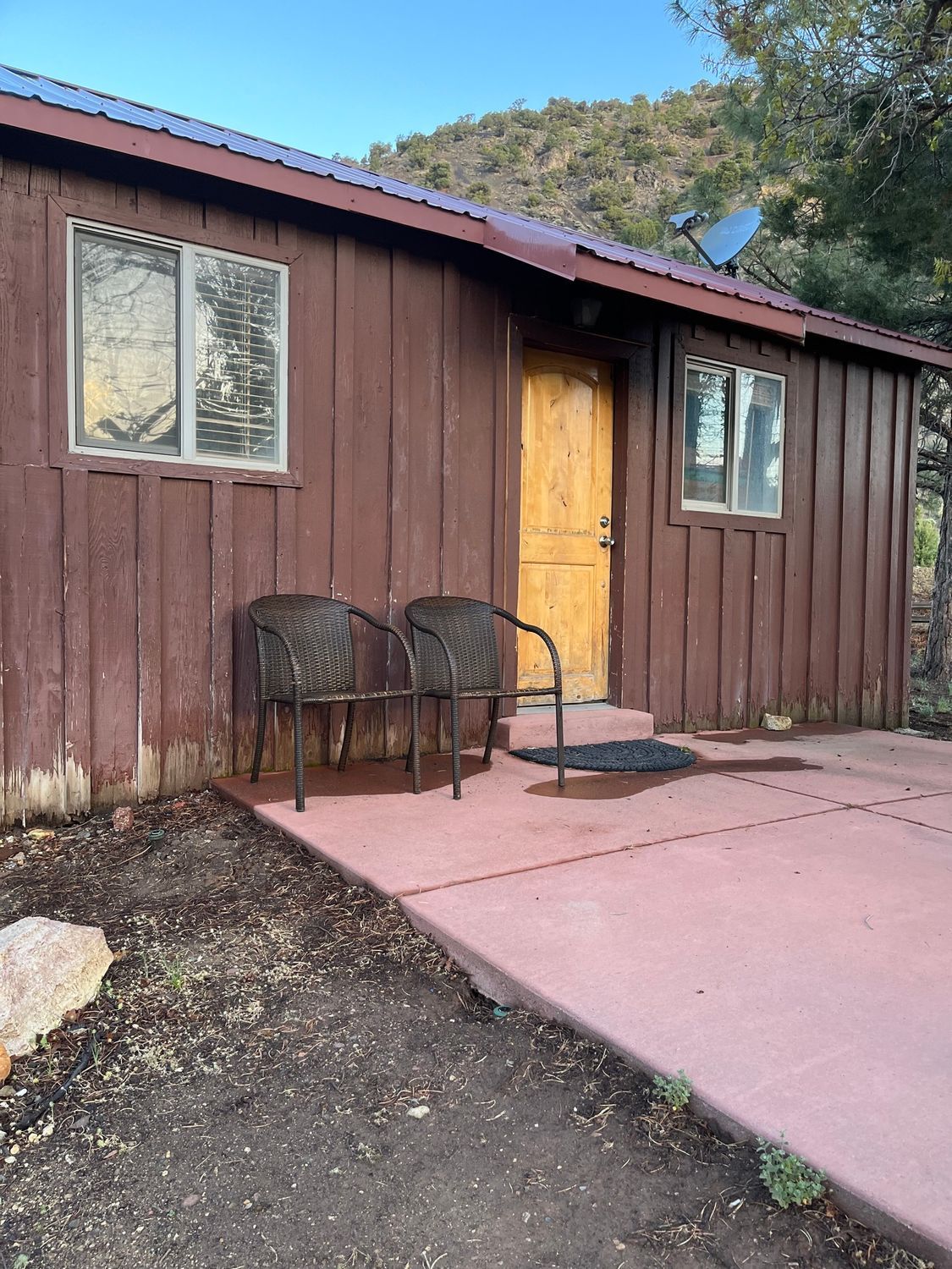 A wooden house with two chairs in front of it.