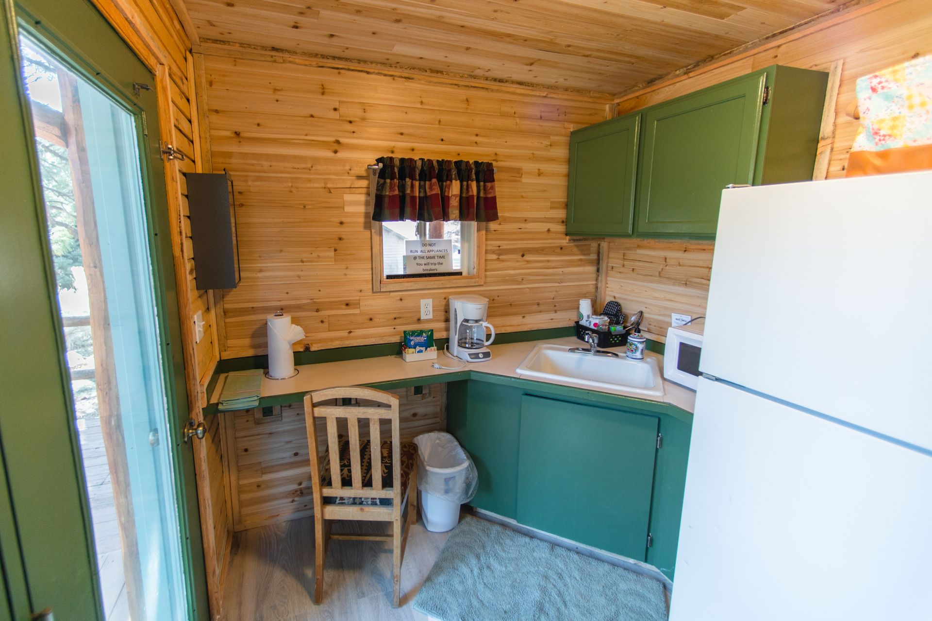 A small kitchen with green cabinets and a white refrigerator.