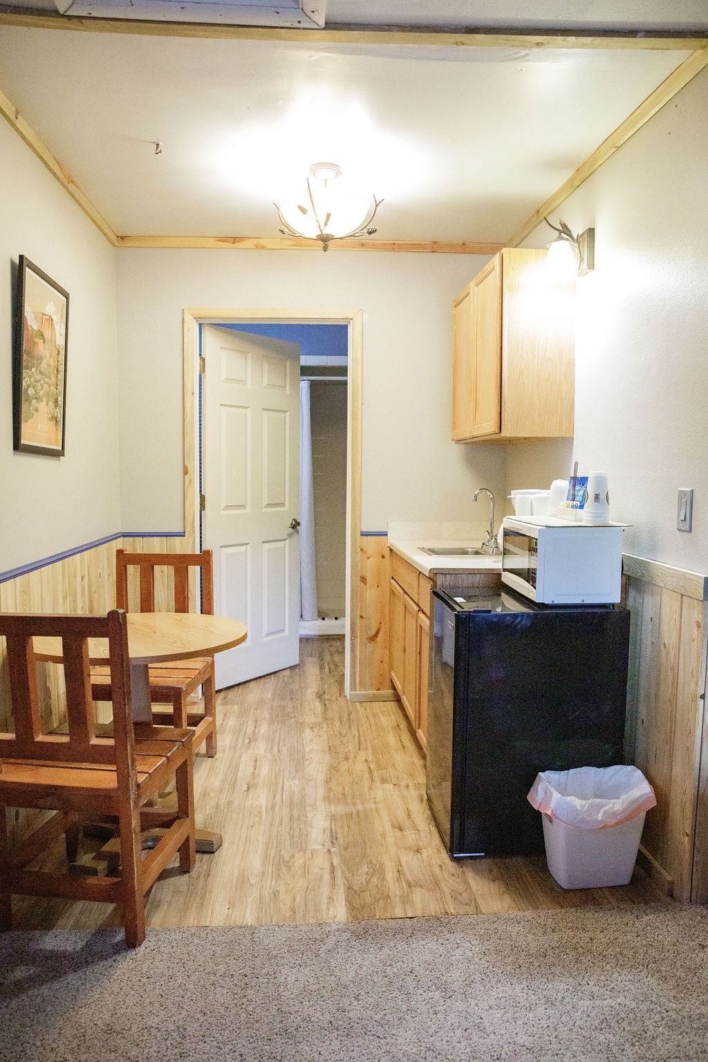 A kitchen with a table and chairs and a trash can.