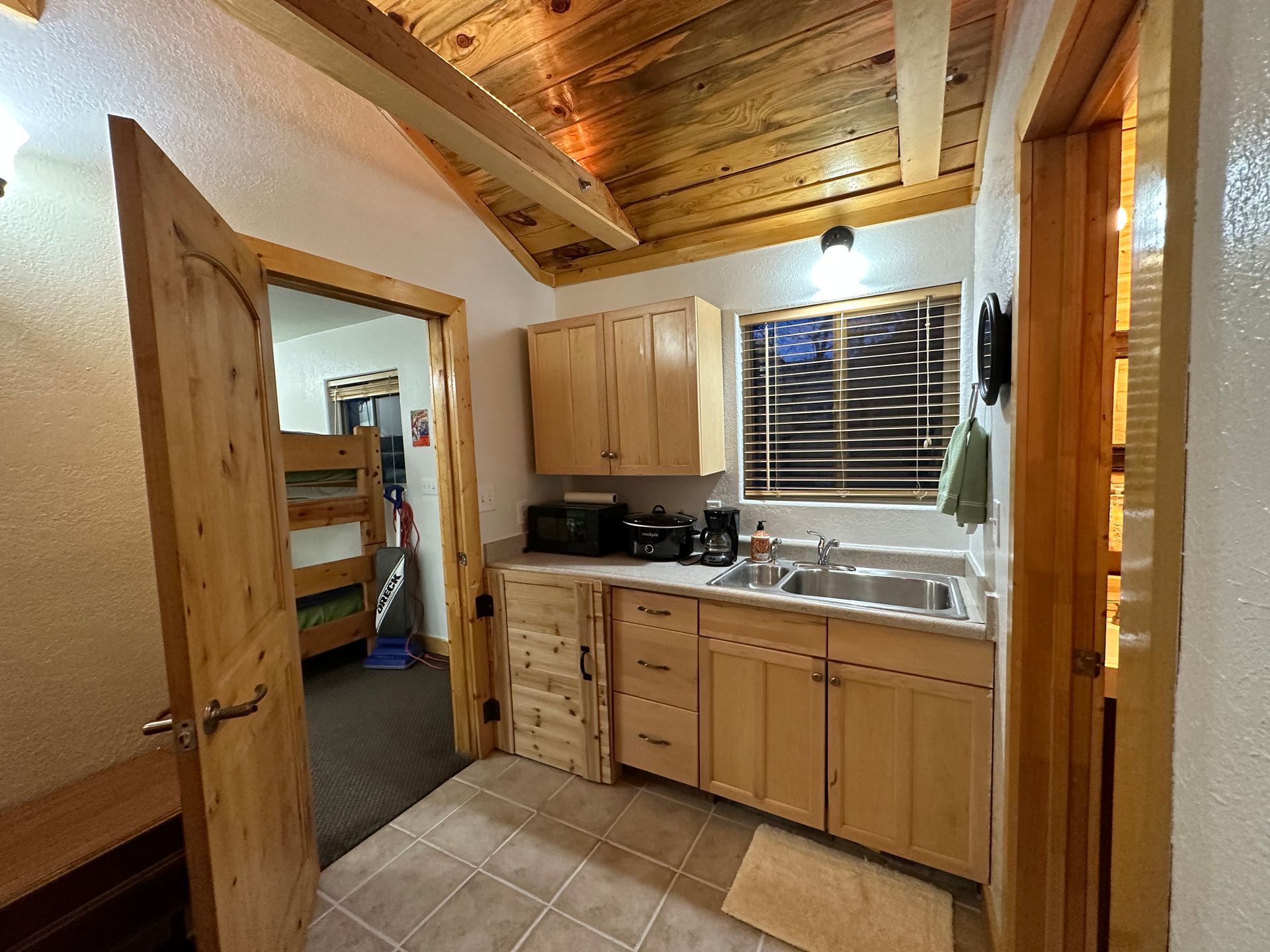 A kitchen in a cabin with wooden cabinets and a sink.