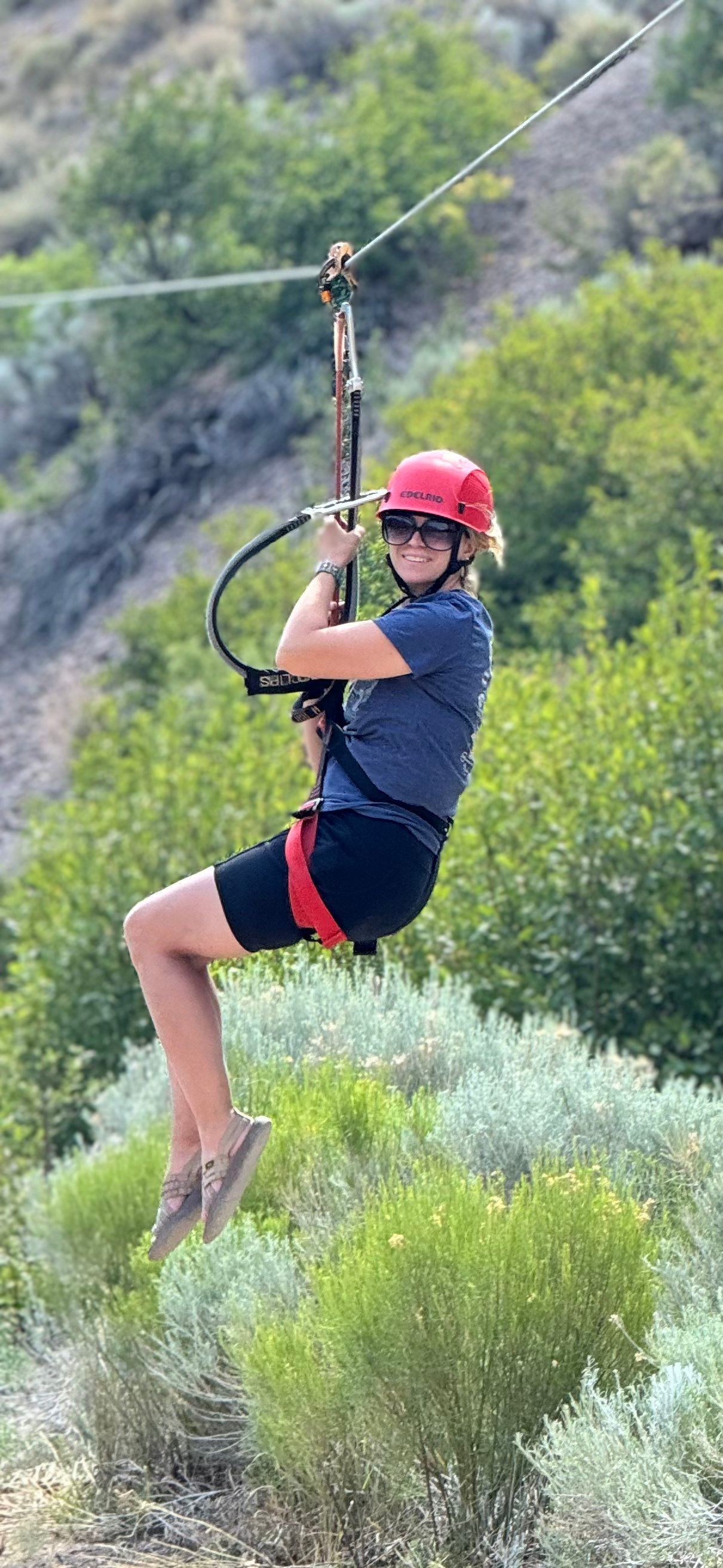 A woman is flying through the air on a zip line.