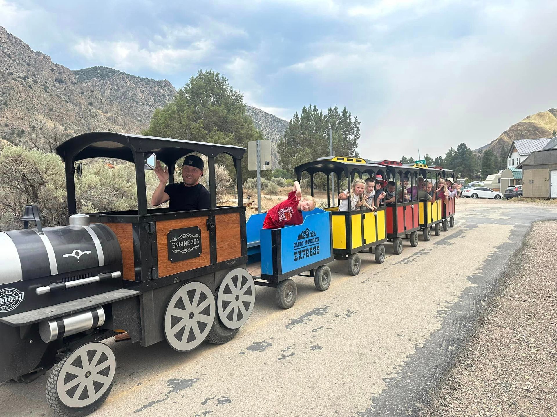 A group of people are riding a small train down a dirt road.