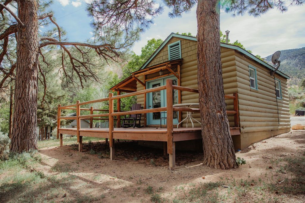 A small log cabin with a large deck surrounded by trees.