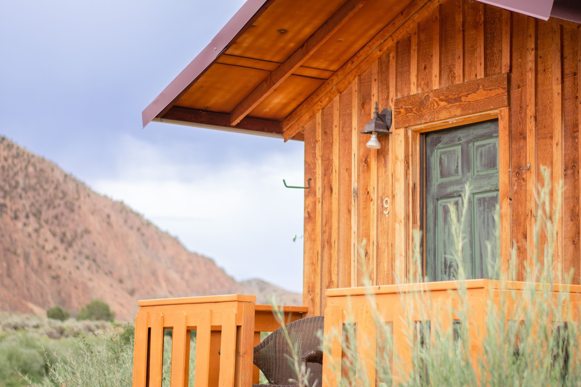 A small wooden cabin with a balcony and mountains in the background.