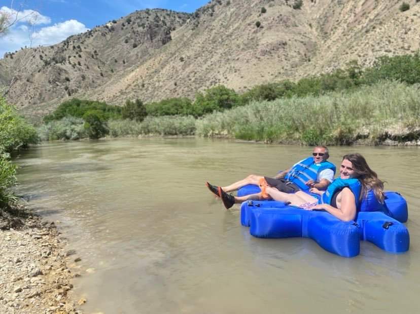 A man and a woman are floating down a river on rafts.