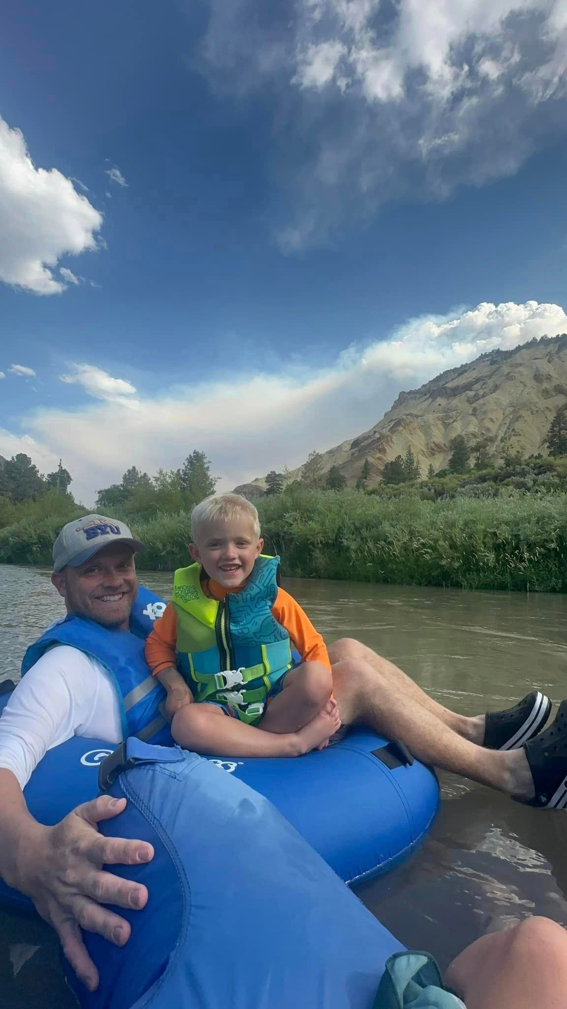 A man and a boy are floating down a river on a tube.