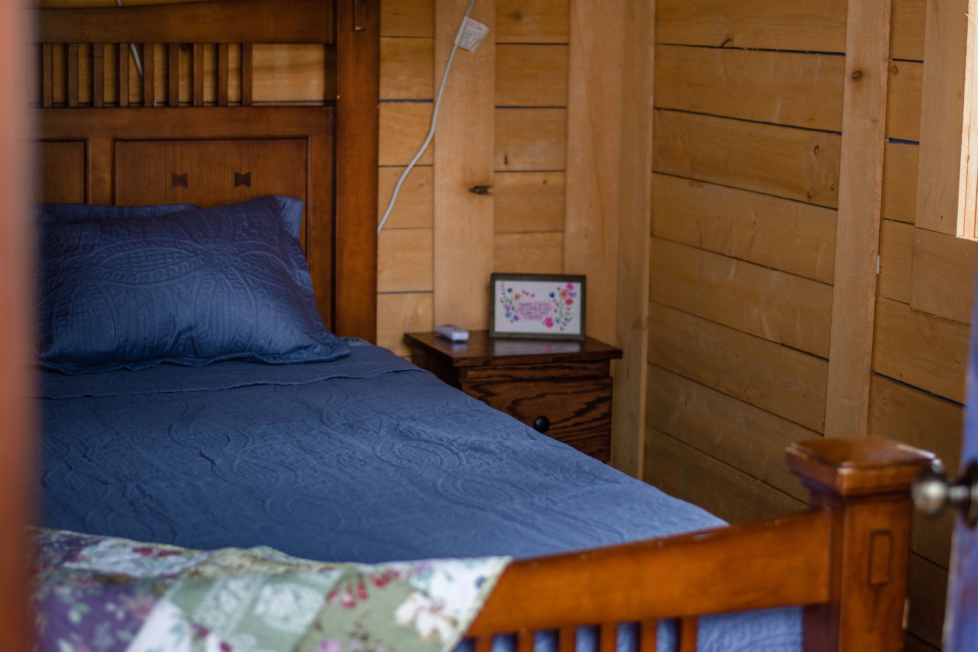 A bed with blue sheets and pillows in a wooden cabin.