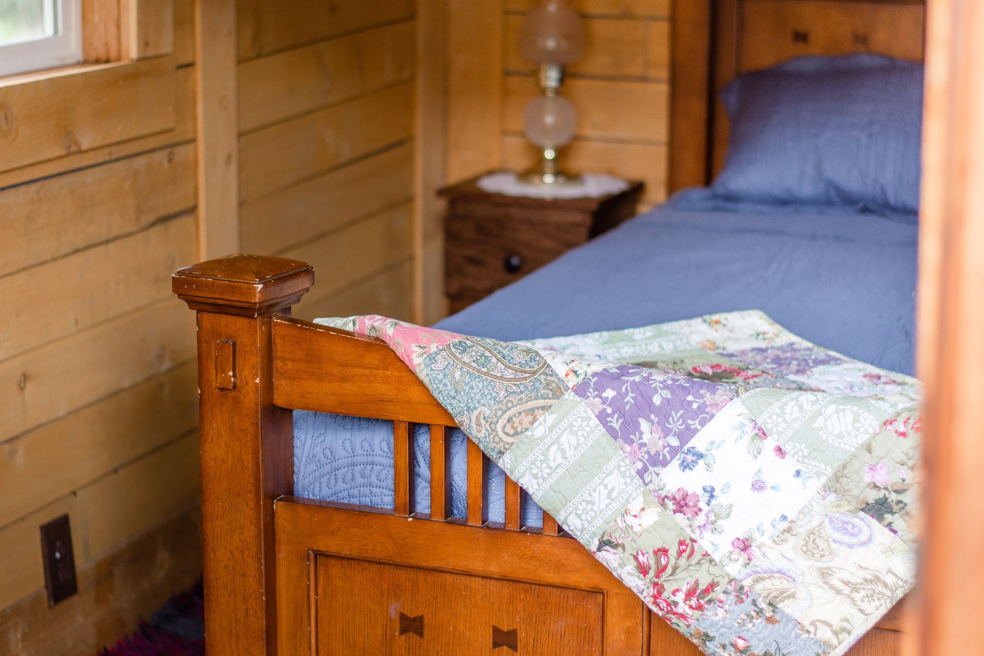 A bed with a blue blanket and a quilt on it