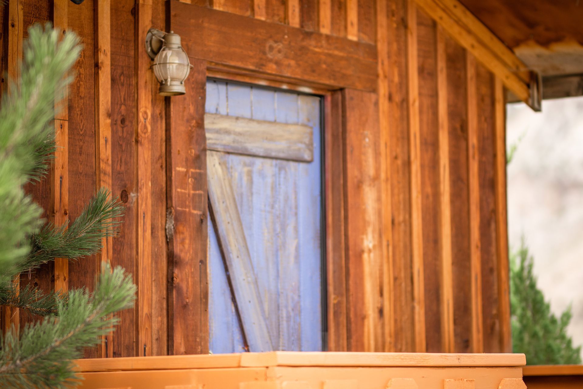 A wooden house with a blue door and a light on the side.