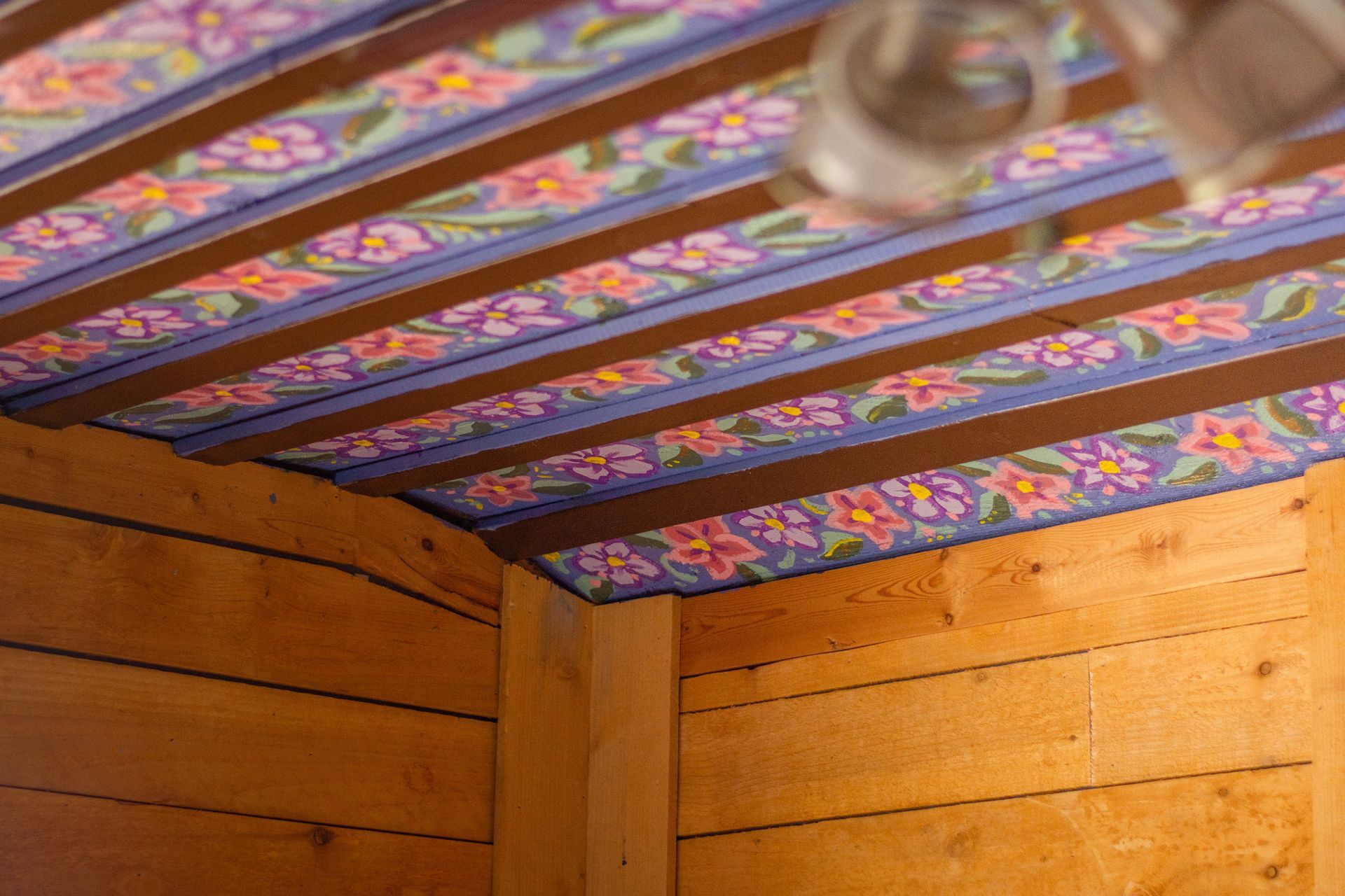 A wooden ceiling with a floral pattern painted on it.