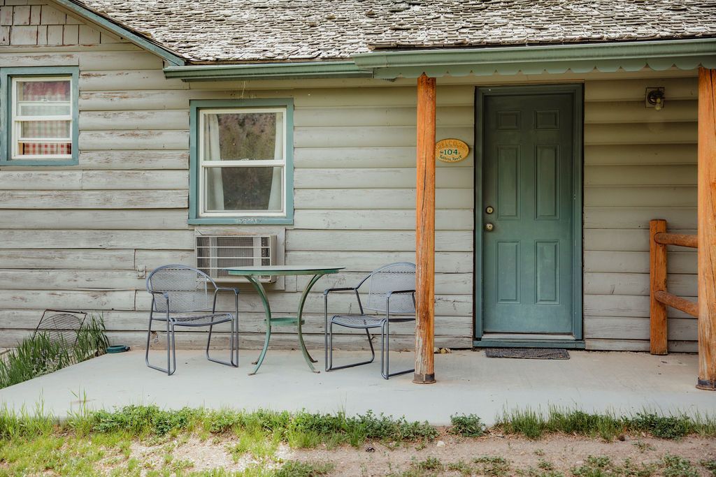 A log cabin with a porch and a table and chairs on it.