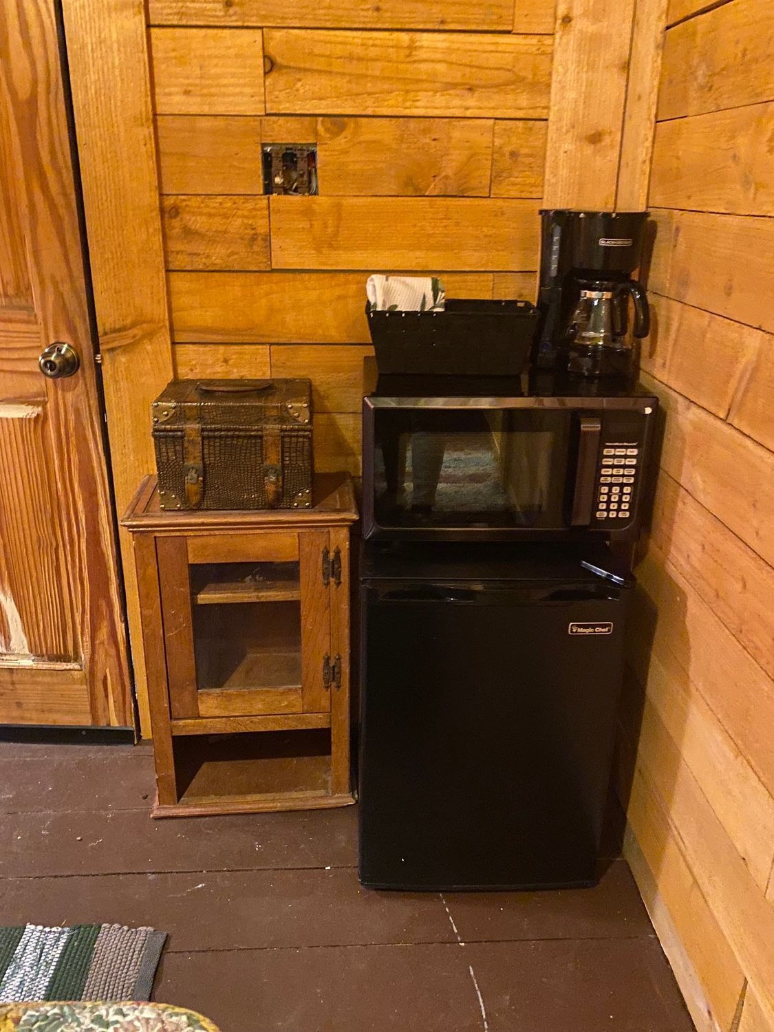 A microwave , refrigerator , and coffee maker are in a wooden room.