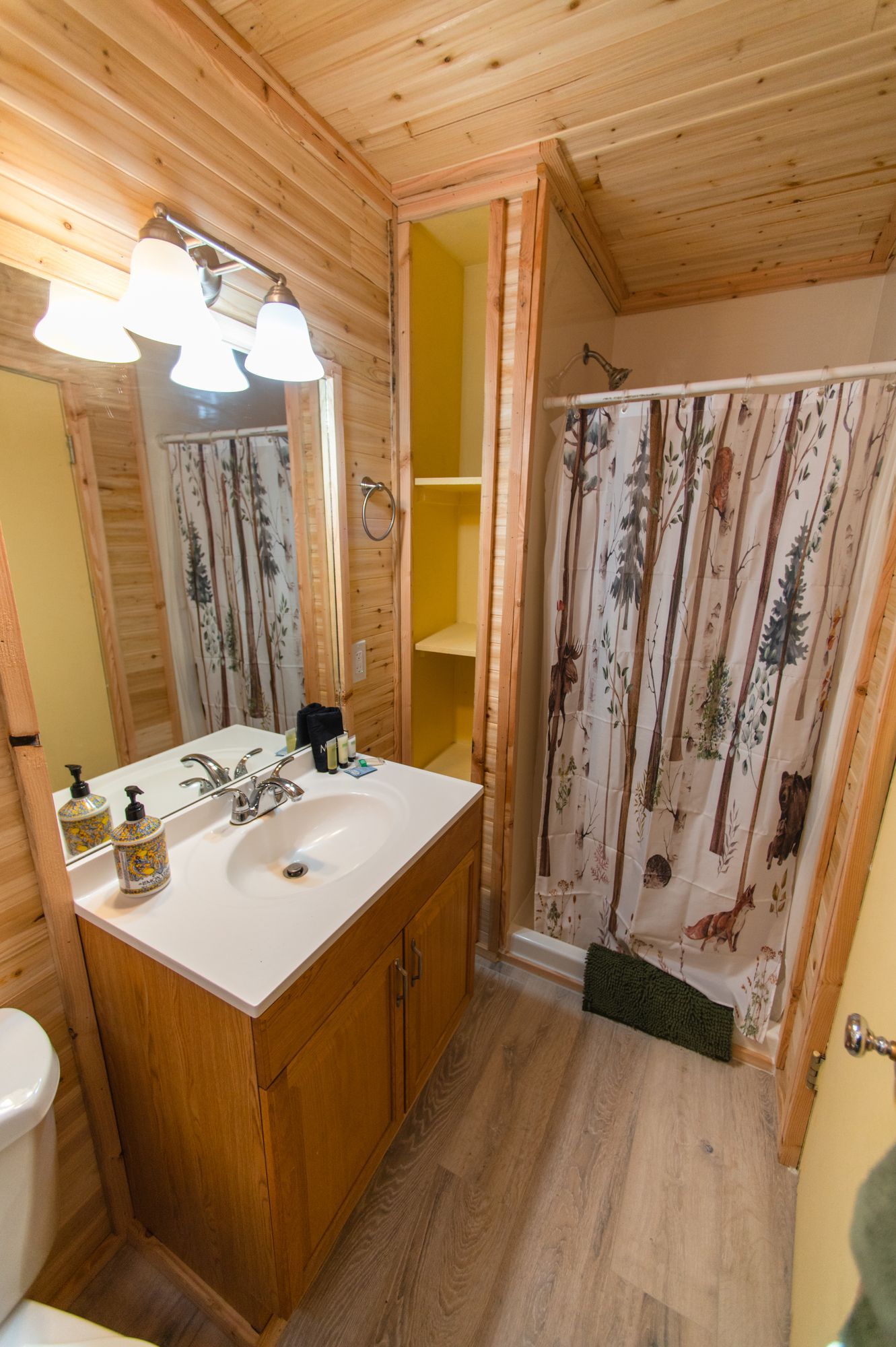 A bathroom with a sink , toilet , mirror and shower curtain.