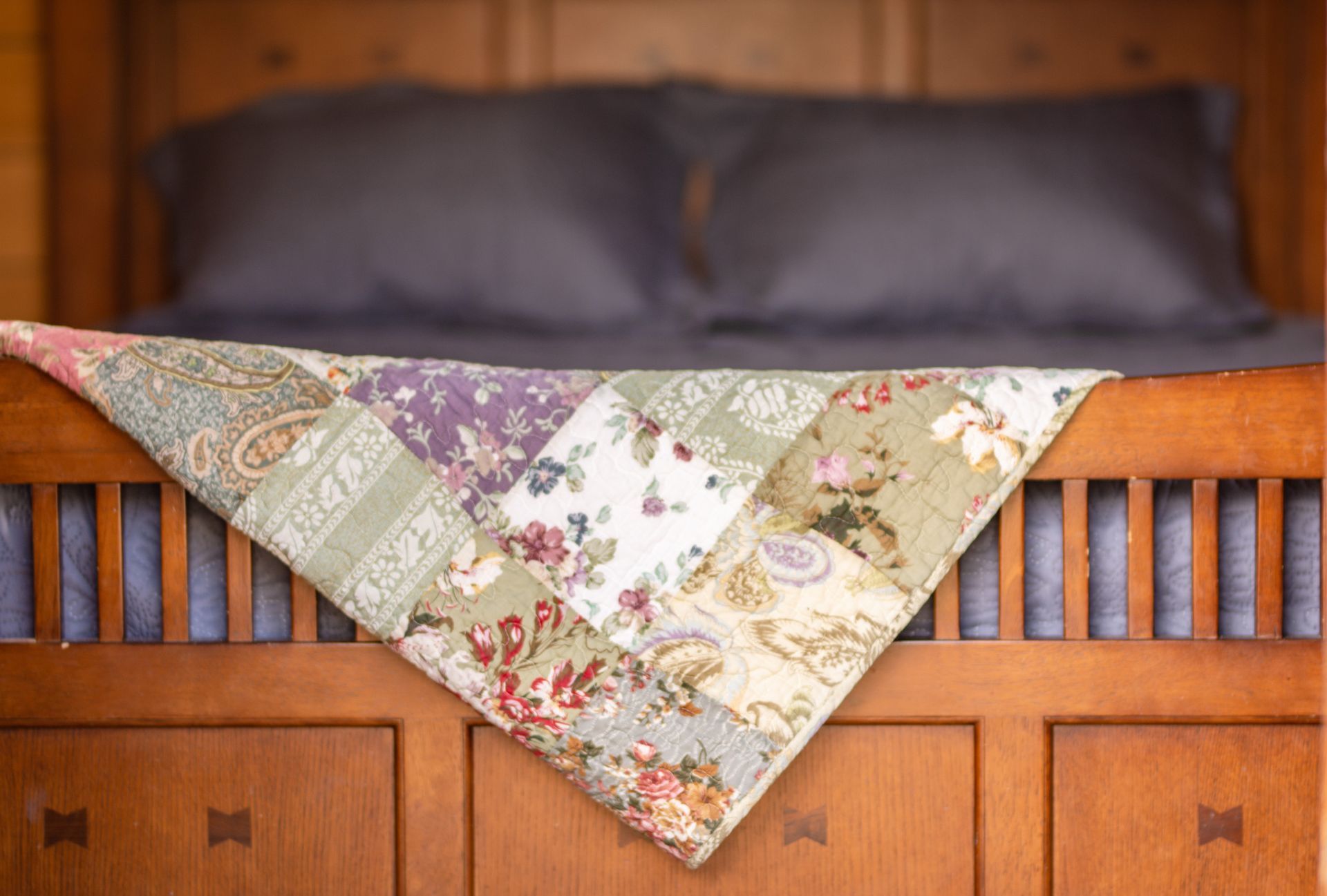 A patchwork quilt is sitting on top of a wooden bed.