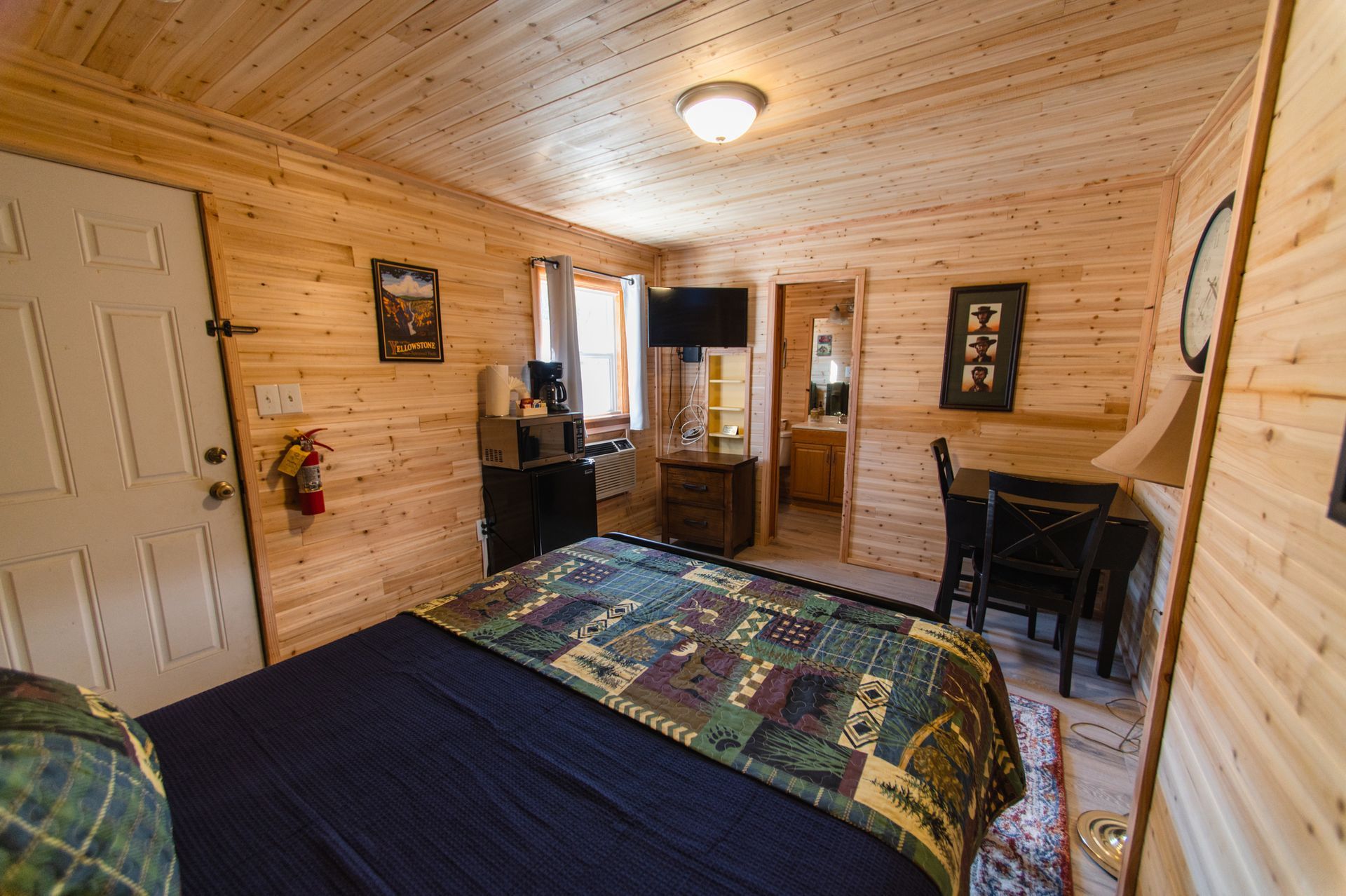 A bedroom in a log cabin with a king size bed and a table and chairs.