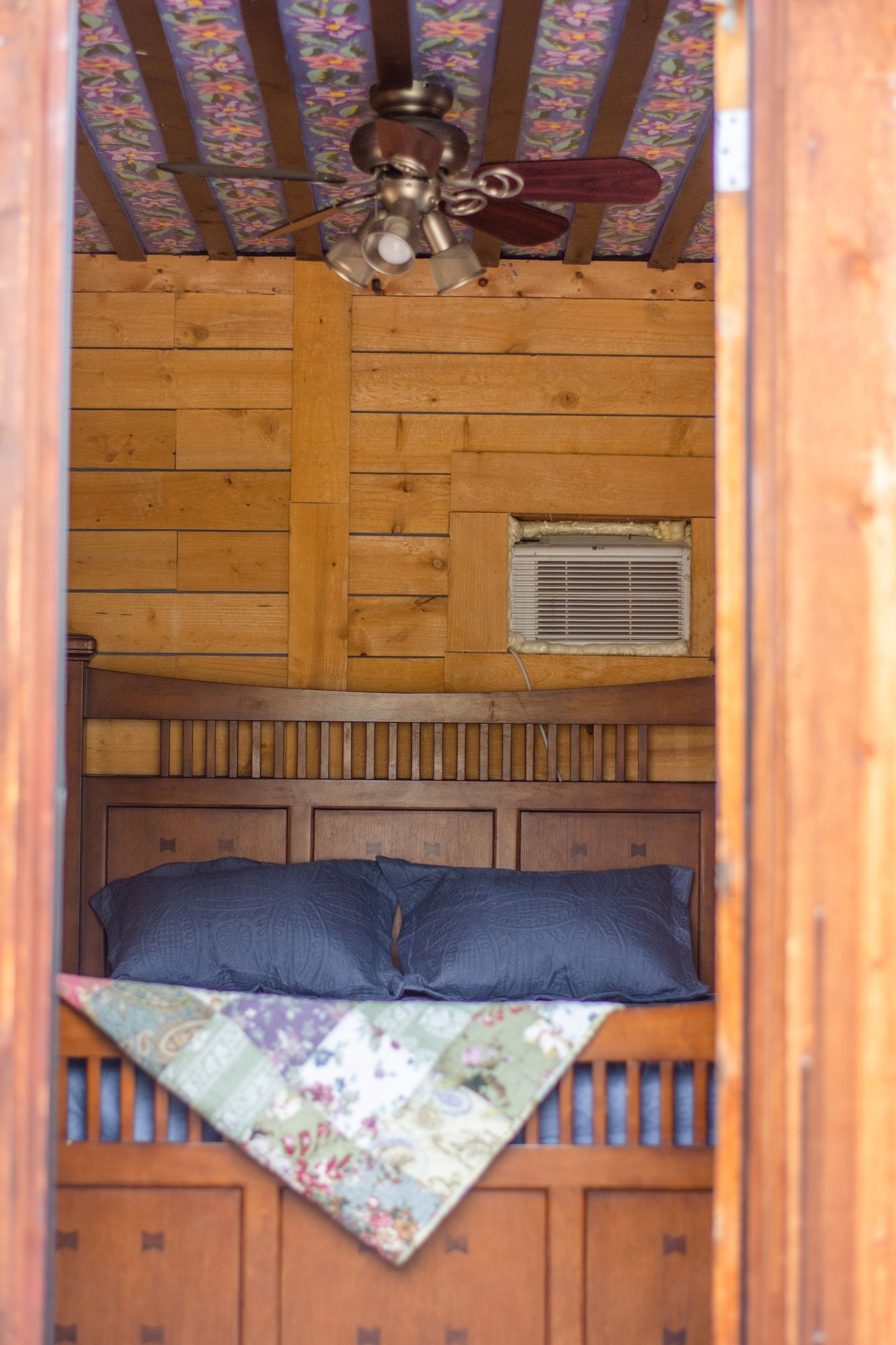 A bedroom with a bed , ceiling fan and air conditioner.