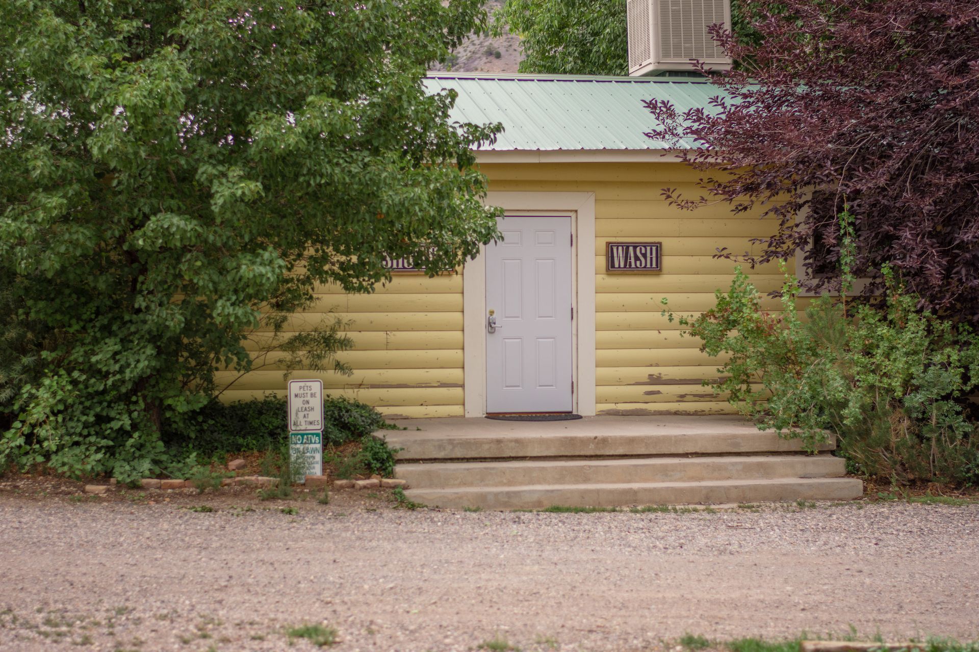 A yellow building with a white door and a sign that says vet