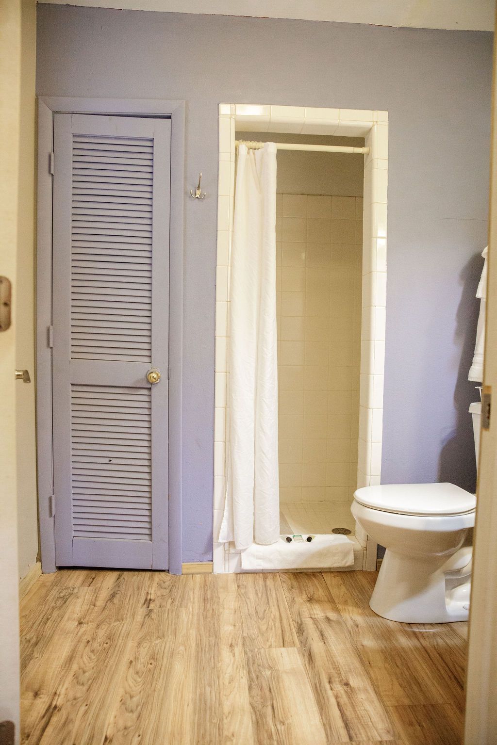 A bathroom with a toilet , shower , and purple walls.