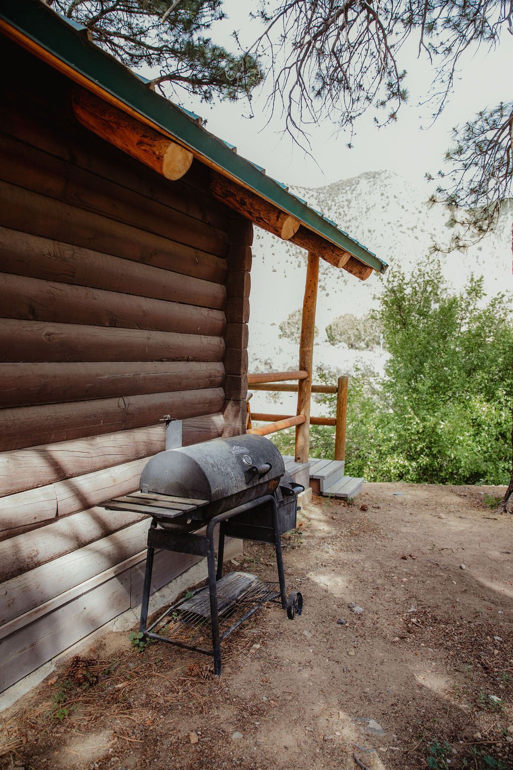 A grill is sitting outside of a log cabin.