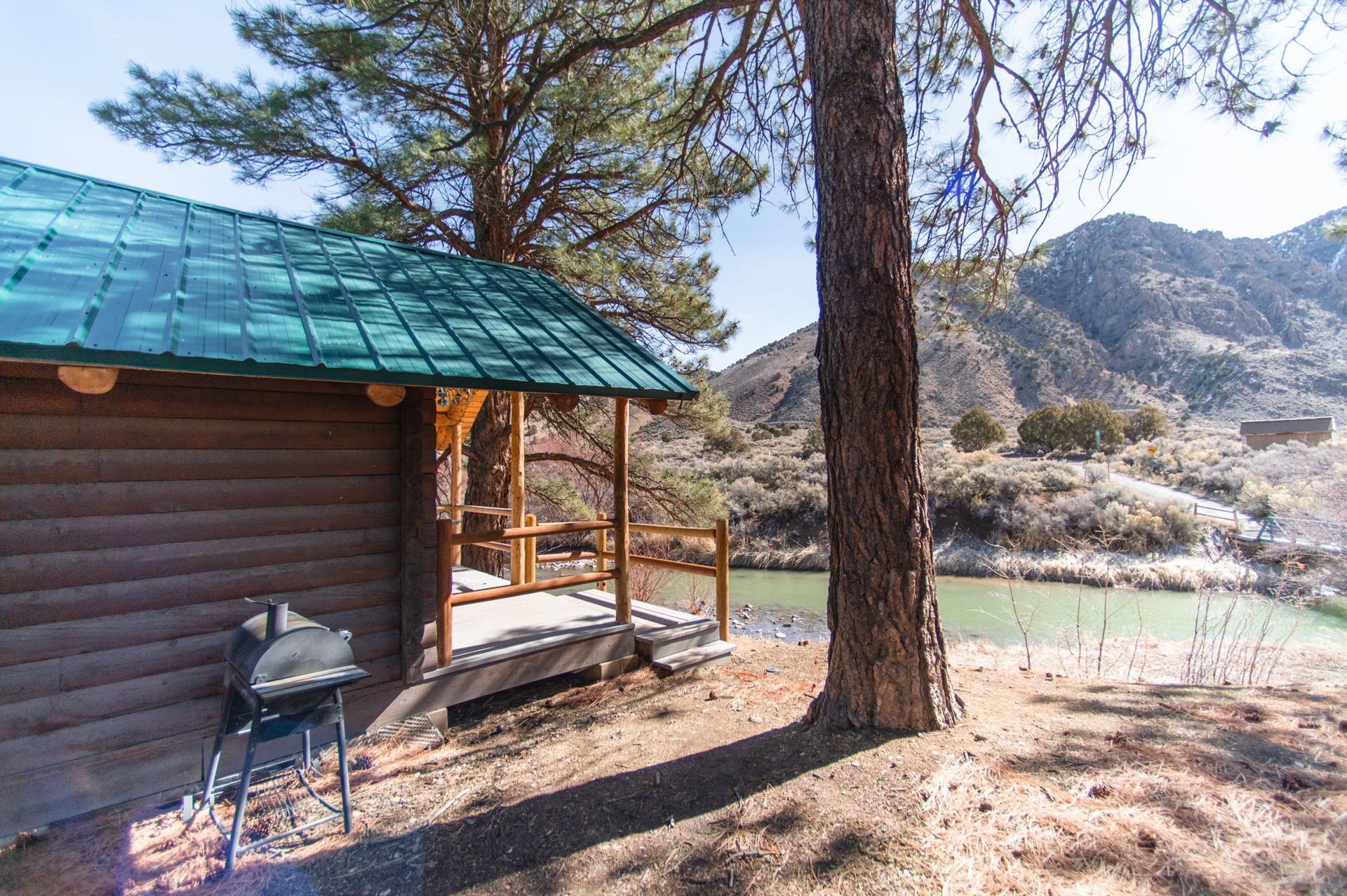 A log cabin with a green roof is sitting next to a lake.