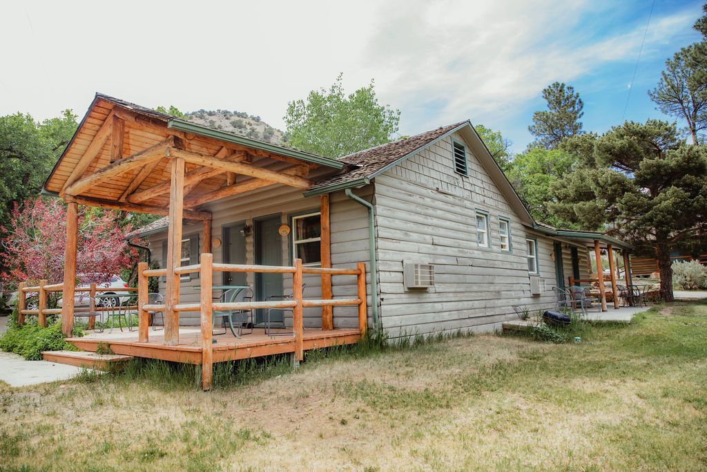 A small white house with a wooden porch in the middle of a field.