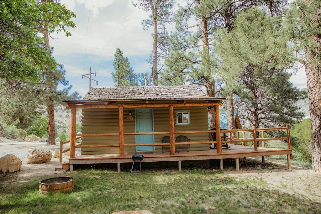 A small cabin with a porch in the middle of a forest.