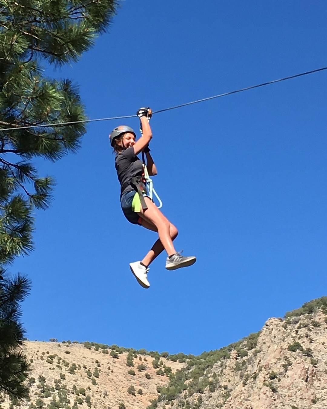 A woman is flying through the air on a zip line