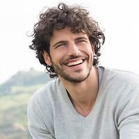 A man with curly hair and a beard is smiling.