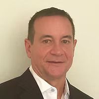 A man in a suit and white shirt is smiling for the camera.