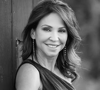 A woman in a black dress is smiling in a black and white photo.